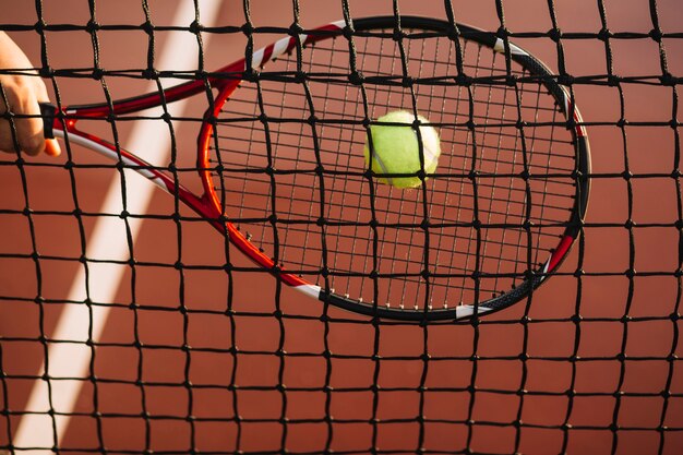 Теннисист бьет по мячу в сетку