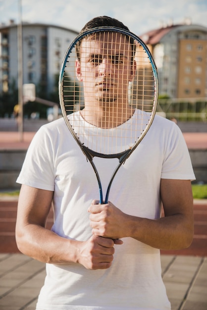 顔の前にラケットを持っているテニス選手