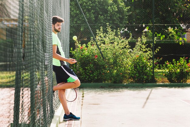 Tennis player leaning against fence