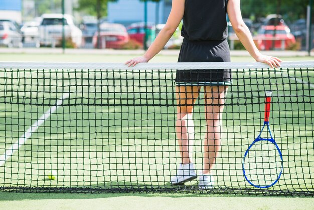 Tennis player with racket standing behind the net