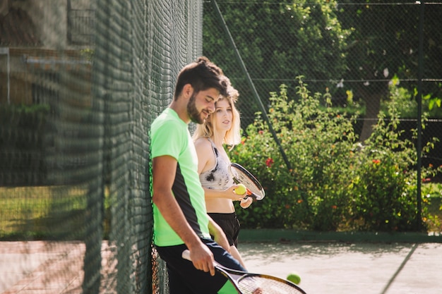 Tennis players leaning against a fence
