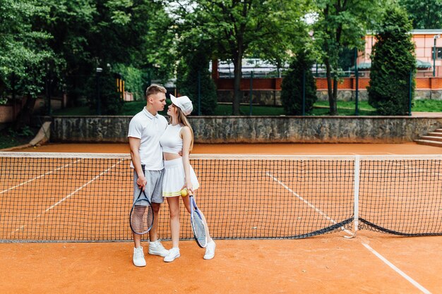 Tennis sport - couple relaxing after playing game of tennis outside in summer.