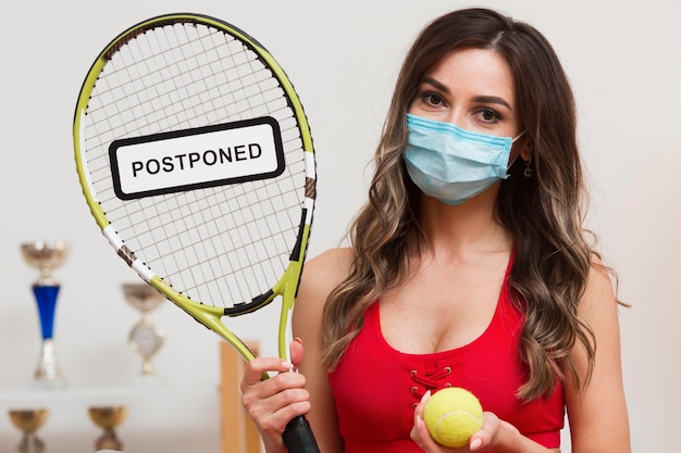 Free photo tennis woman holding a postponed sign on her racket