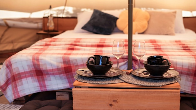 Tent interor with bed and dishes at glamping