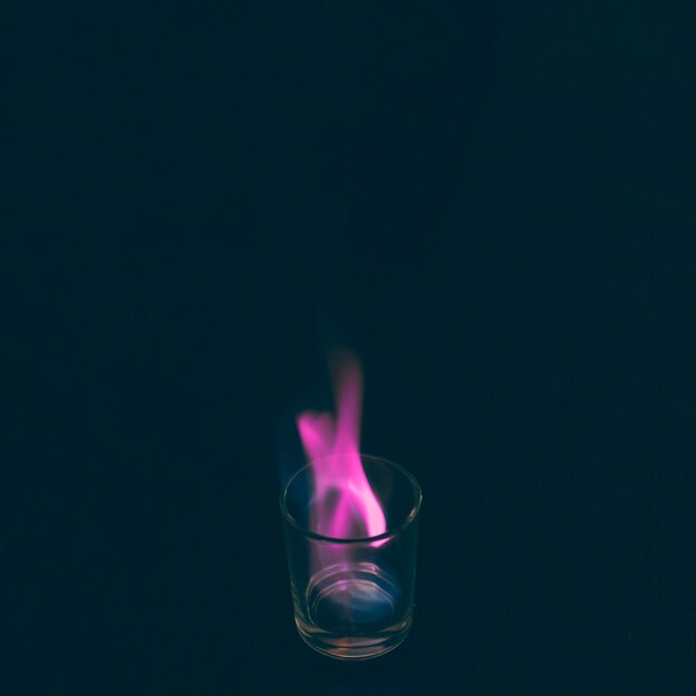 Tequila shot glass burning with pink flame