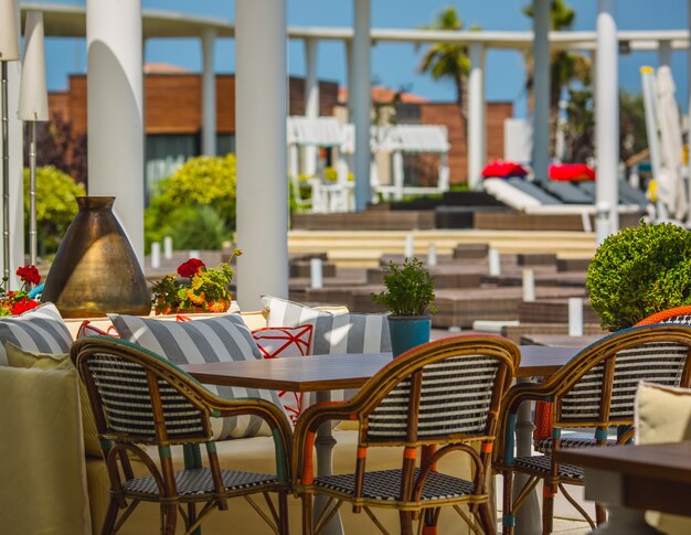 Terrace of a hotel stuffed with soft furnitures in a green space.