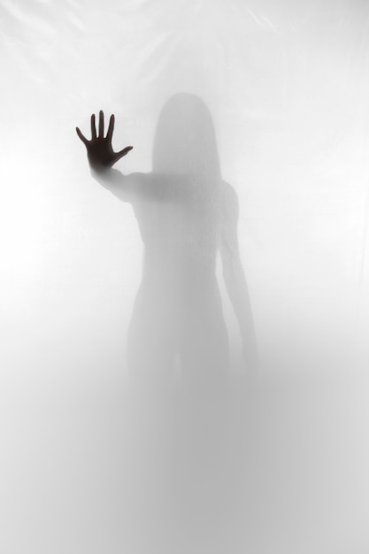 Free photo terrifying hand silhouette with translucent curtain