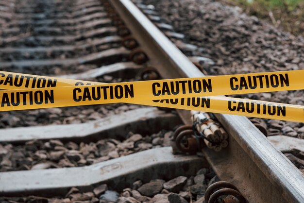 テロの概念。危険な爆発物が鉄道の上に横たわっています。前に黄色の注意テープ