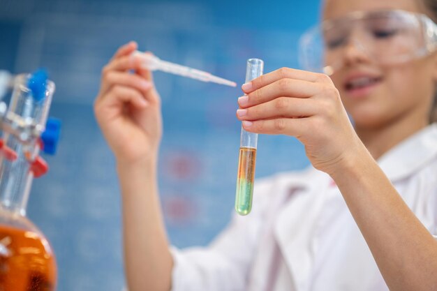 Test tube with liquid in hand of girl