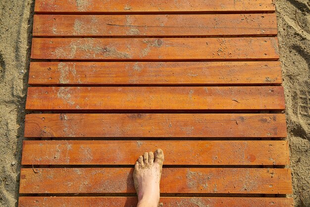 Texture of wooden boards with sand and a foot