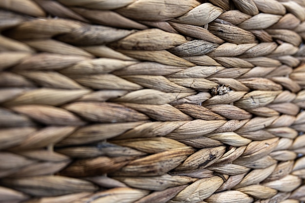 Texture of woven beige straw, background of braids from the plant stem close-up.