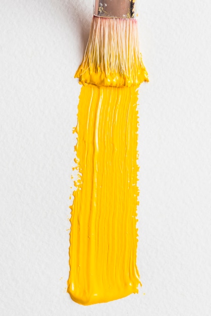 Текстурированный мазок желтой краски возле кисти