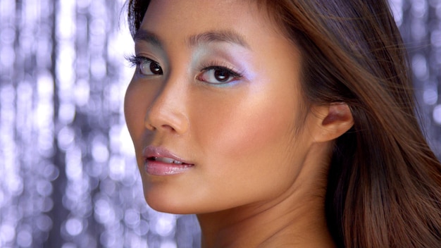 Thai asian model in studio with silver rain disco background and party makeup Closeup portrait