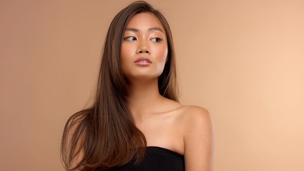 ベージュの背景にナチュラルメイクのタイのアジア人モデル