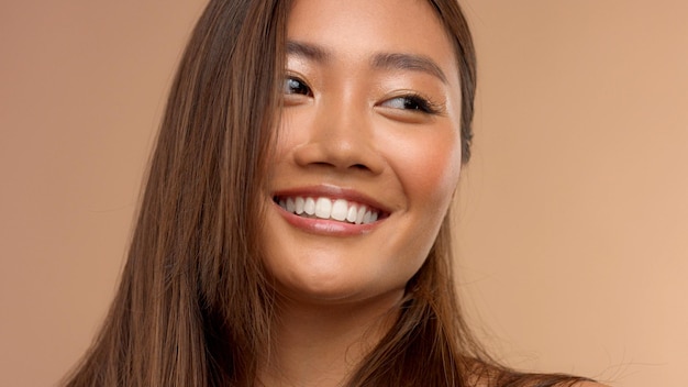 Тайская азиатская модель с натуральным макияжем на бежевом фоне
