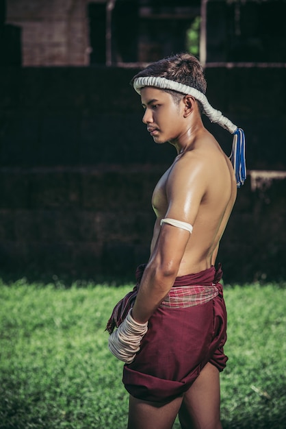 Free photo thai boxers wrap the tape in the hands and stand on the lawn.