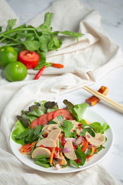 Тайская еда; смешанный острый салат из белых свиных колбасок или YUM MOO YOR