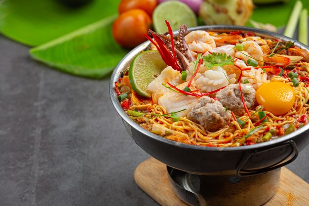 Тайская еда. лапша острая отварная с морепродуктами и свининой в горшочке