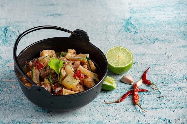 Thai food with spicy pork leg soup in black bowl