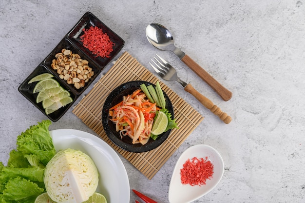 Thai papaya salad in a white plate with sticky rice and dried shrimps