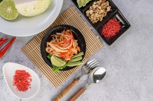 Thai papaya salad in a white plate with sticky rice and dried shrimps