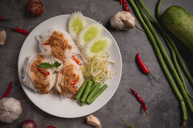 Thai rice noodles in fish curry sauce on wooden table.