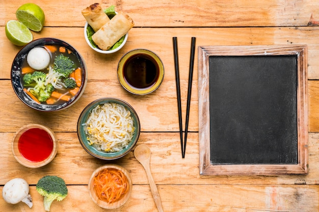 Thai soup; spring rolls; sauces and sprout beans with chopstick over the wooden table