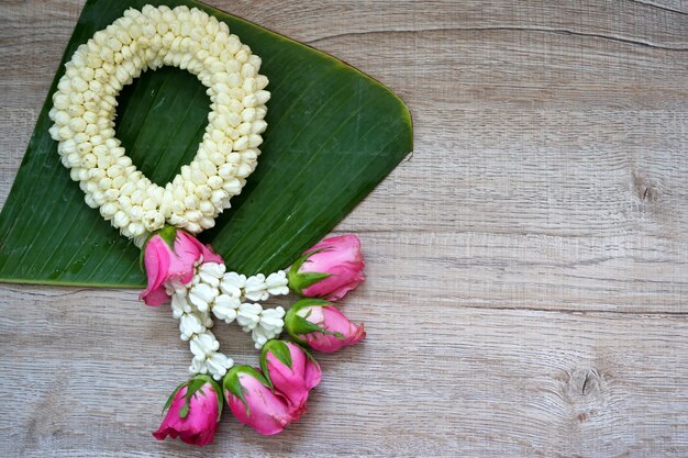 バナナの葉と木製の背景にジャスミンの花輪のタイスタイル Premium写真