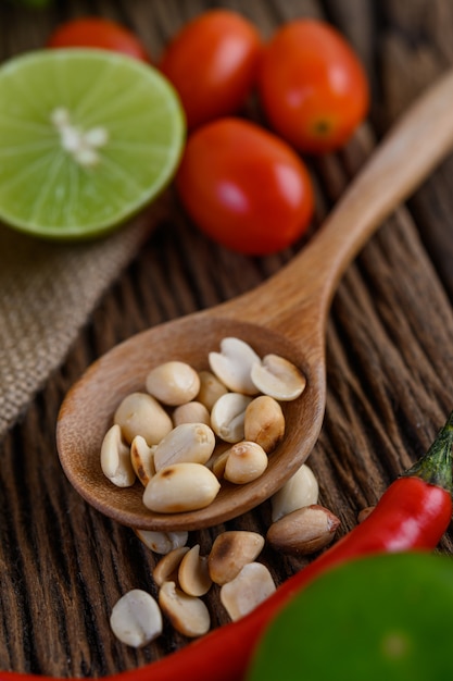 Thai style spicy food, Som Tum food concept, props decoration Garlic, lemon,  tomatoes, chili and peanuts on wood spoon on wood table