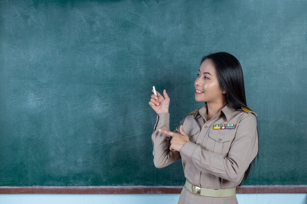 Тайский учитель в официальной одежде преподает перед щитом