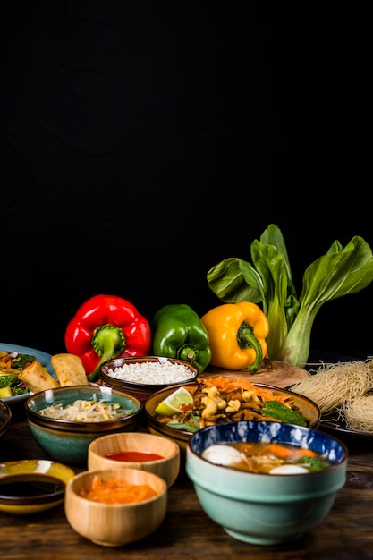 Thai traditional food with bell peppers and bokchoy over table against black background