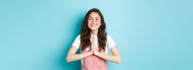 Free photo thank you smiling cute girl showing namaste gratitude gesture asking for help or favour smiling plea