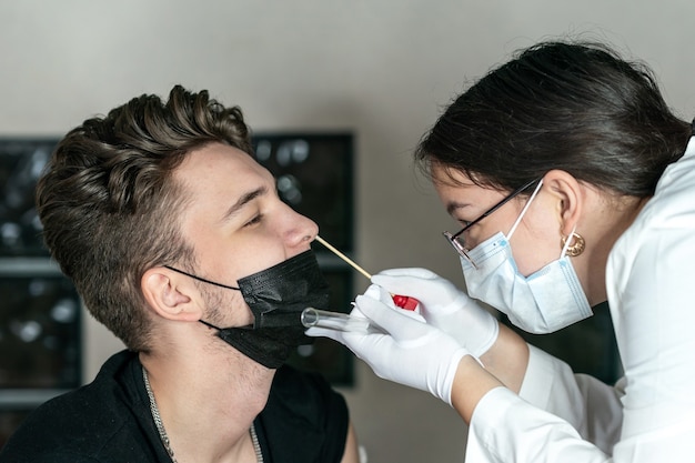 医者​は​若い​男​の​鼻​の​dna​検査​pcr​検査​から​綿棒​を​取ります
