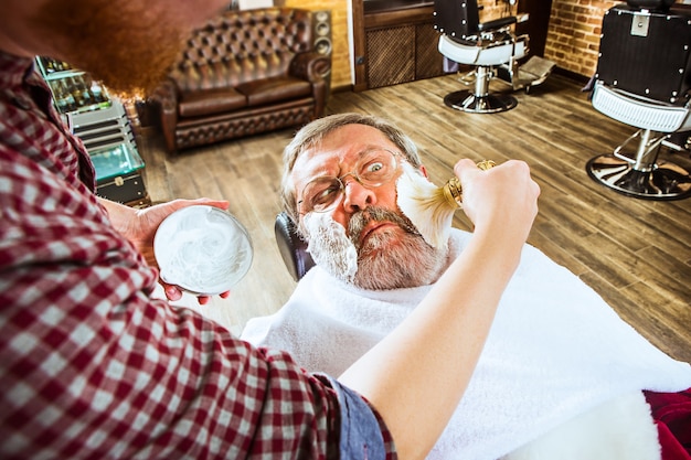 Бесплатное фото Эмоциональный старший мужчина, посещающий парикмахера в парикмахерской