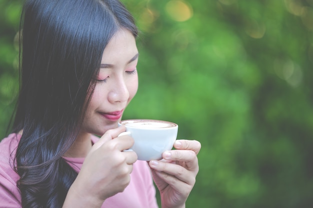 무료 사진 소녀는 커피 숍에서 기쁨으로 커피를 마시고 있습니다.