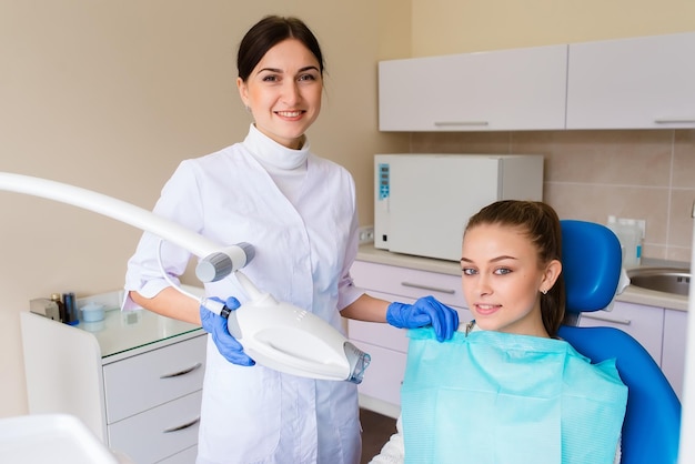 Девушка улыбается в стоматологии, пациент стоматолог, гоночная модель в стоматологической клинике белые ухоженные зубы после приема у врача отбеливание зубов и зубная эмаль