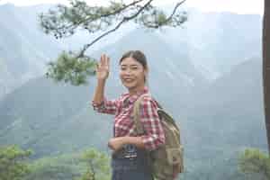 무료 사진 소녀는 정글의 배낭과 함께 열대 숲의 언덕 꼭대기에서 손을 흔들었다. 모험, 하이킹.