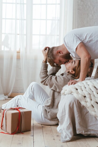 ベッドの上の男が床に座っている女の子にキスをします 無料の写真
