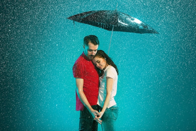 無料写真 背景色が水色の傘と雨の中で愛するカップル