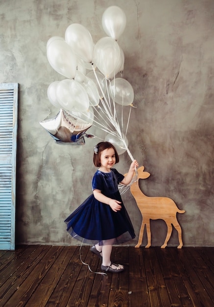 Бесплатное фото Маленькая девочка держит баллоны в комнате