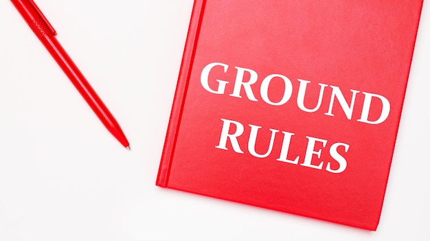 Ground rules라는 텍스트는 사무실의 흰색 테이블에 있는 빨간색 펜 근처에 있는 빨간색 메모장에 쓰여 있습니다. 비즈니스 개념