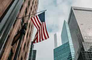 無料写真 曇り空の下で高層ビルの近くの旗竿に米国またはアメリカ合衆国の旗
