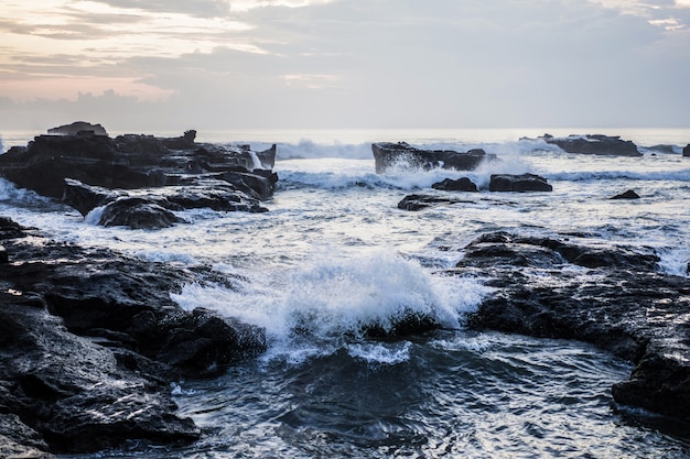 海の波が岩に砕けている。日没時に波が飛び散る。