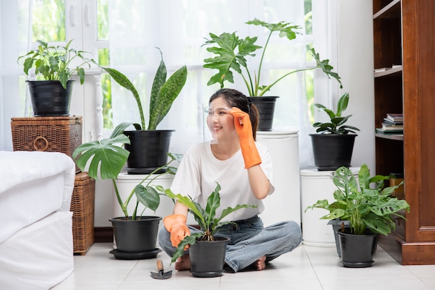 女性はオレンジ色の手袋を着用し、家に木を植えました。