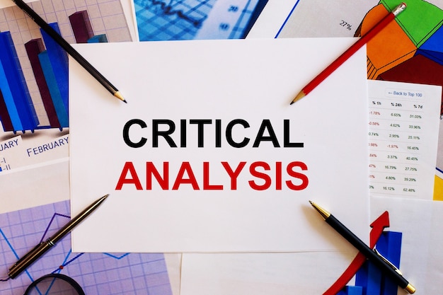 Critical analysis​という​言葉​は​、​色付き​の​グラフ​、​ペン​、​鉛筆​の​近く​の​白い​表面​に​書かれています