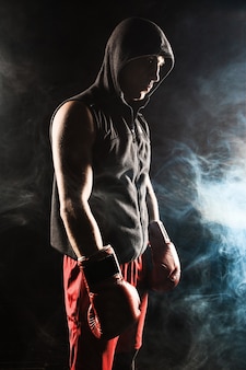 青い​煙​の​背景​に​立っている​若い​男性​アスリートキックボクシング