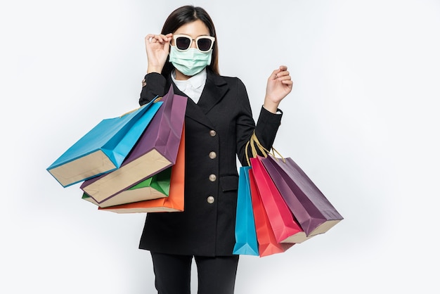 젊은 여성은 쇼핑하러 가기 위해 어두운, 마스크, 안경과 가방을 입고 있었다