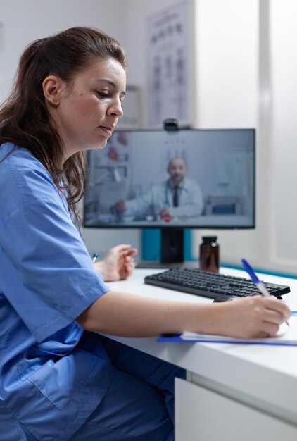 Therapist nurse discussing sickness diagnostic with remote doctor during online videocall meeting conference during clinical consultation in hospital office. Telemedicine call on computer screen