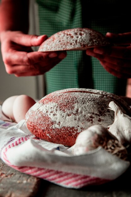 Thin sliced black bread, man puting a slice in the hand and egg bowl on white towel with garlic. side view.