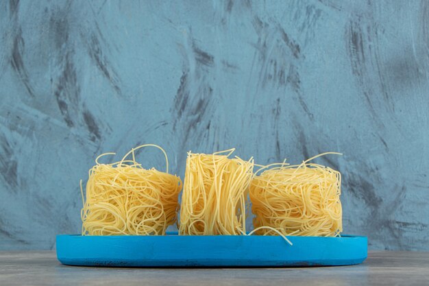 Тонкие спагетти-гнезда на синей тарелке